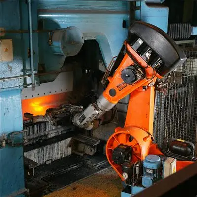 Orange robot arm beside a glowing opening in industrial machinery.