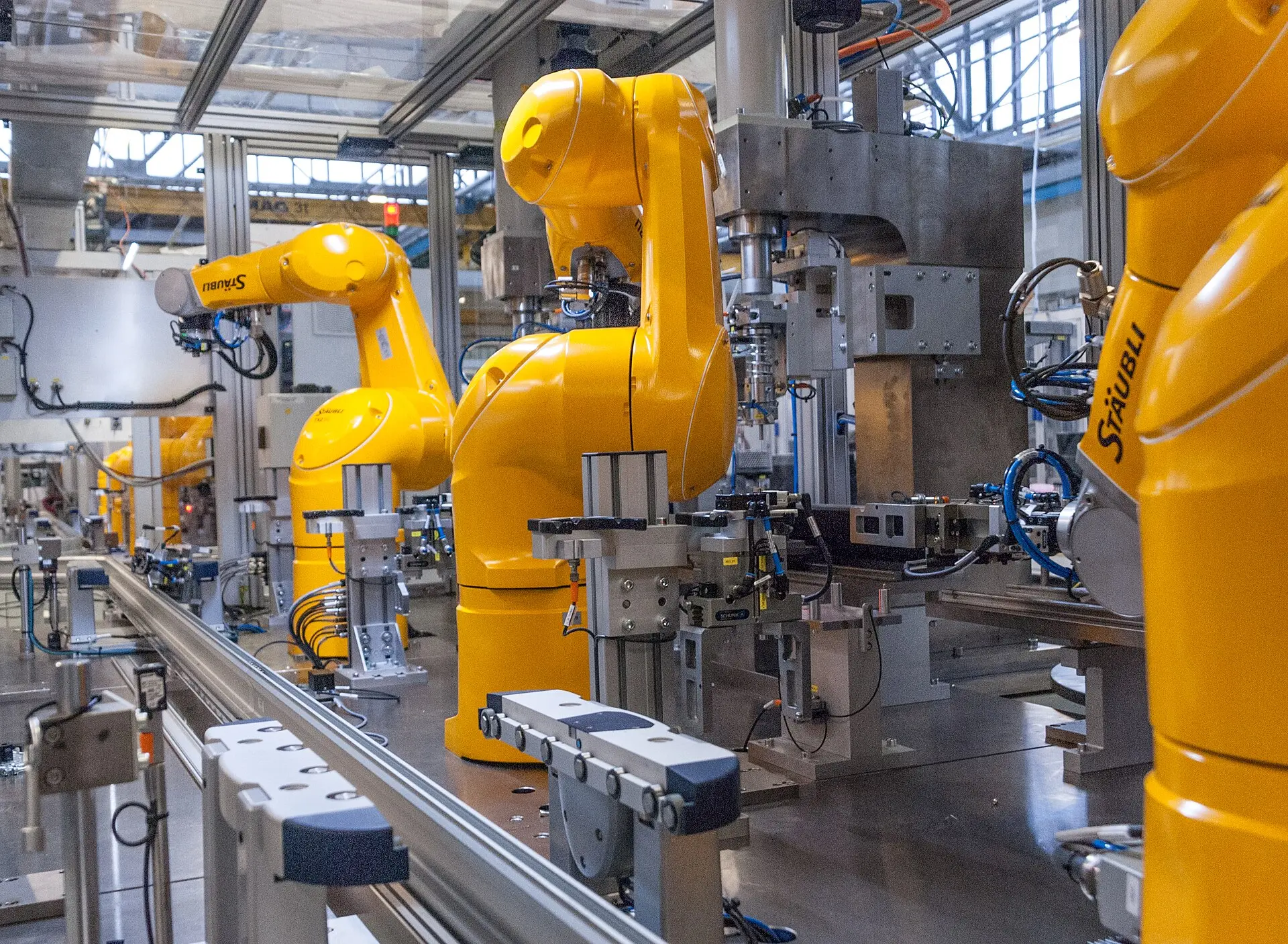 Yellow robot arms beside fixtures and production equipment.